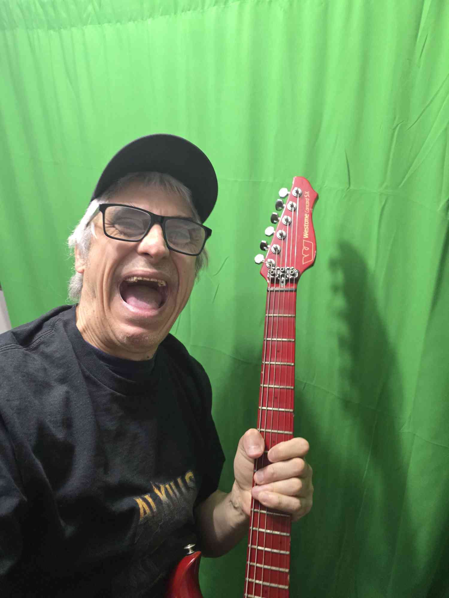 Todd Russell holding a red guitar in front of a dramatic fiery scene.